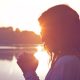 side view of woman clasping hands together with a sunset behind her
